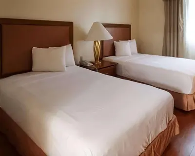 a hotel room with two beds and a lamp at Rodeway Inn South Miami - Coral Gables in Miami