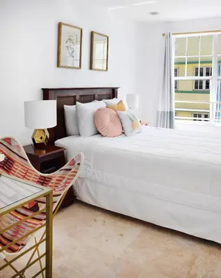 a white bedroom with two beds and a chair at Beach Park Hotel in Miami Beach