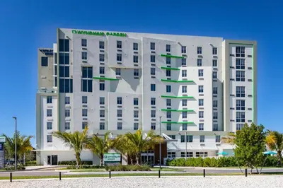 a white building with a green sign on it at Wyndham Garden Miami International Airport in Miami