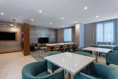 a waiting room with tables and chairs and a tv at Wyndham Garden Miami International Airport in Miami