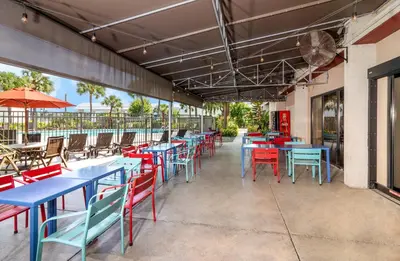 an empty patio with blue tables and red chairs at Red Roof PLUS Miami Airport in Miami