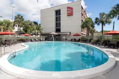 a large swimming pool in front of a hotel at Red Roof PLUS Miami Airport in Miami