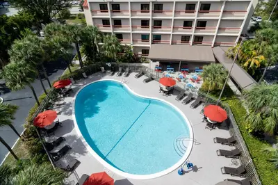 an overhead view of a swimming pool with red umbrellas at Red Roof PLUS Miami Airport in Miami