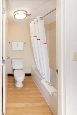 a bathroom with a toilet and a shower curtain at Red Roof PLUS Miami Airport in Miami