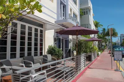 a patio with chairs and umbrellas next to a building at Shelley Hotel in Miami Beach