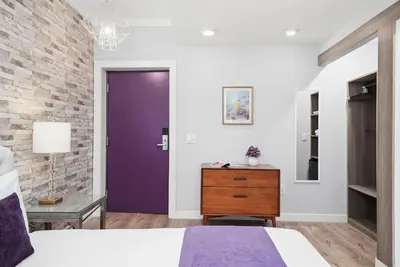 a bedroom with a purple door and a brick wall at Shelley Hotel in Miami Beach