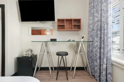 a desk in a room with a tv and a stool at Chesterfield Hotel & Suites in Miami Beach
