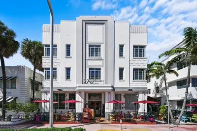 a white building with red umbrellas in front of it at Whitelaw Hotel in Miami Beach