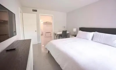 a bedroom with a large white bed and a table at Designer River View Apartments in Fort Lauderdale