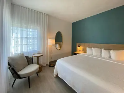 a bedroom with a bed and a chair and a window at Marseilles Beachfront Hotel in Miami Beach