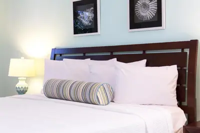 a bedroom with a white bed with white pillows at Dorchester Hotel & Suites in Miami Beach