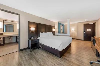 a large hotel room with a bed and a mirror at Comfort Inn & Suites Miami International Airport in Miami