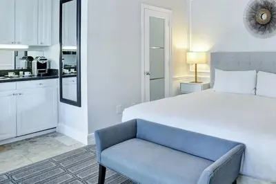 a white bedroom with a bed and a blue couch at The Pillars Hotel & Club in Fort Lauderdale