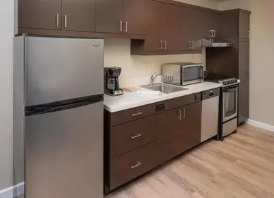 a kitchen with brown cabinets and a refrigerator at TownePlace Suites Miami Kendall West in Kendall
