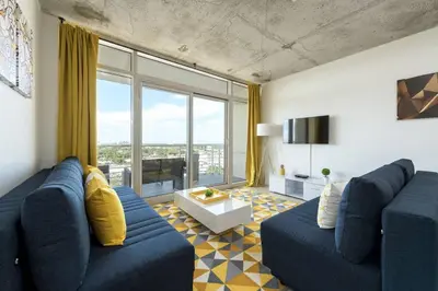 a living room with a blue couch and a large window at Modern 1 Bedroom Midtown Miami with FREE Parking in Miami