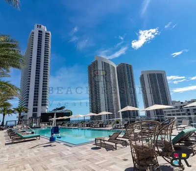 a pool with chairs and umbrellas in front of buildings at HYDE Beach House Apartments in Hollywood