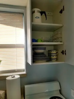 a kitchen with a cupboard with dishes and a window at Guayabita's House in Miami