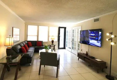 a living room with a couch and a flat screen tv at Alexander 1211 Beachfront Condo with Direct Beach Access, 2 Pools, Sauna, Gym in Miami Beach