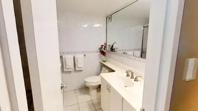 a white bathroom with a toilet and a sink at Alexander 511 Beachfront condo with 2 pools, direct beach access, sauna, tikki bar in Miami Beach