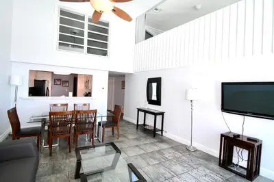 a living room with a table and chairs and a flat screen tv at Castle M16 Oceanview Loft with Beach access, Pool, Tennis and Free Parking! in Miami Beach