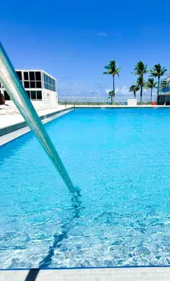 a swimming pool with blue water and palm trees at Castle M16 Oceanview Loft with Beach access, Pool, Tennis and Free Parking! in Miami Beach