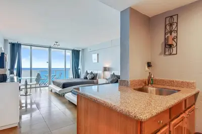 a kitchen with a sink and a living room at Castle 828 Oceanfront view with balcony, pool, tennis, beach access and free parking! in Miami Beach