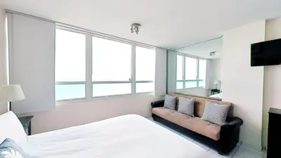 a bedroom with a bed and a couch and windows at Castle 1033 in Miami Beach