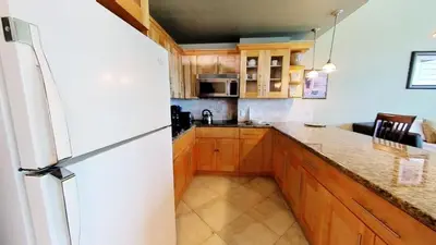 a kitchen with a white refrigerator and wooden cabinets at Castle B17 Contemporary Condo with Pool, Beach Access and Free Parking in Miami Beach
