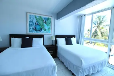 two beds in a blue room with a window at Castle Th16 Beachfront Townhouse with private patio, direct beach access, pool, tennis & free parking! in Miami Beach