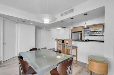 a kitchen and dining room with a glass table and chairs at Steps to the Sand Beachfront Escape- 25th Floor Views in Miami Beach