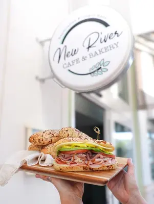 a person holding a sandwich on a cutting board at Riverside Hotel in Fort Lauderdale