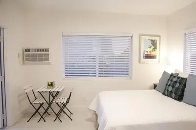 a white bedroom with a bed and a table and chairs at Apt 1 Miami Designer Studio in the Upper East-Side in Miami