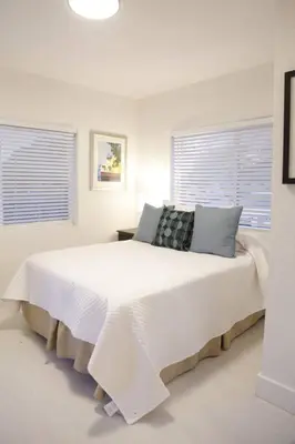 a white bedroom with a large white bed with two windows at Apt 1 Miami Designer Studio in the Upper East-Side in Miami