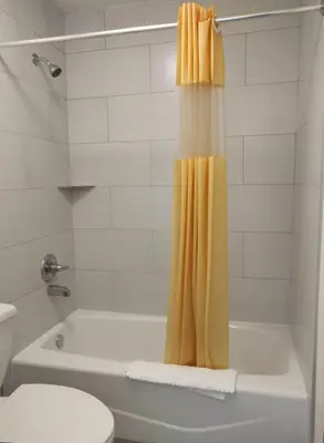 a bathroom with a tub and a yellow shower curtain at Red Carpet Inn Airport Fort Lauderdale in Fort Lauderdale