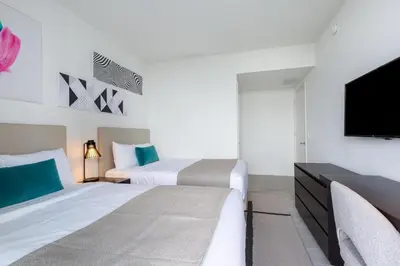 two beds in a hotel room with a tv at Ocean Breeze Retreat - Pool Gym Access Views in Hallandale Beach