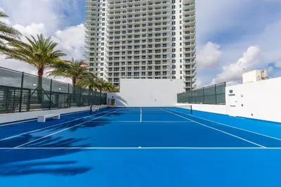 a tennis court in front of a tall building at Ocean Breeze Retreat - Pool Gym Access Views in Hallandale Beach
