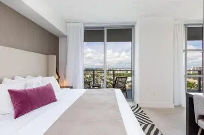 a bedroom with a large bed with a large window at Ocean Breeze Retreat - Pool Gym Access Views in Hallandale Beach