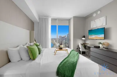 a bedroom with a bed with a desk and a window at Luxury 2Br Front Ocean & Bay View, Amazing Pools in Hollywood