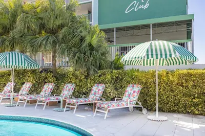 a group of chairs and umbrellas next to a pool at Palm Tree Club Miami in Miami Beach