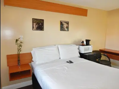 a bedroom with a white bed with a desk and two pictures at Haven Hotel - Fort Lauderdale Airport & Cruise Port in Fort Lauderdale