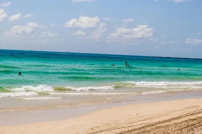 a group of people in the water at the beach at Welworth condo units Miami Beach in Miami Beach