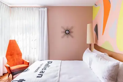 a bedroom with a bed and a chair and a window at Pelican Hotel in Miami Beach