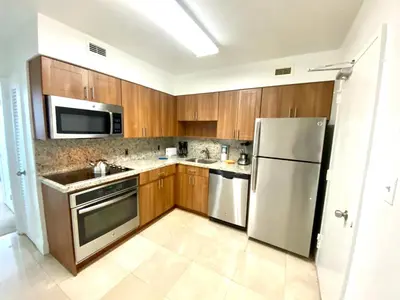 a kitchen with wooden cabinets and a stainless steel refrigerator at Seacoast by Miami Ambassadors in Miami Beach