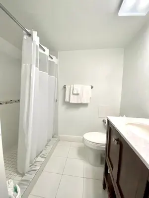 a white bathroom with a shower and a toilet at Seacoast by Miami Ambassadors in Miami Beach