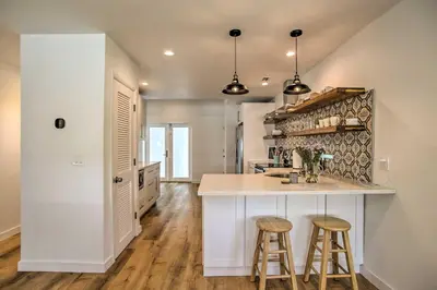 a kitchen with a counter and two bar stools at Modern Home with Shared Pool in Fort Lauderdale! in Fort Lauderdale