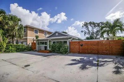 a house with a fence in front of a driveway at Modern Home with Shared Pool in Fort Lauderdale! in Fort Lauderdale