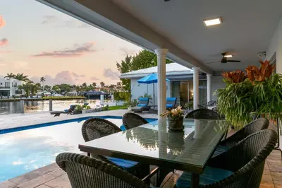 a patio with a table and chairs next to a swimming pool at Waterfront Fort Lauderdale House with Heated Pool! in Fort Lauderdale