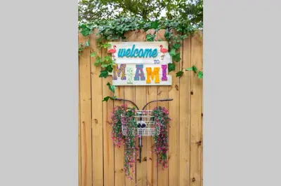 a fence with a welcome sign and flowers on it at Casa Madeira @ the heart of Miami Design District in Miami