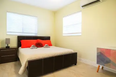 a bedroom with a bed with red pillows and a tv at Family, Couples Retreat near Airport, Cruise Port & Beaches in Fort Lauderdale