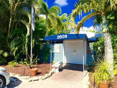 a blue garage with a blue roof and palm trees at Coral Reef Guesthouse in Fort Lauderdale